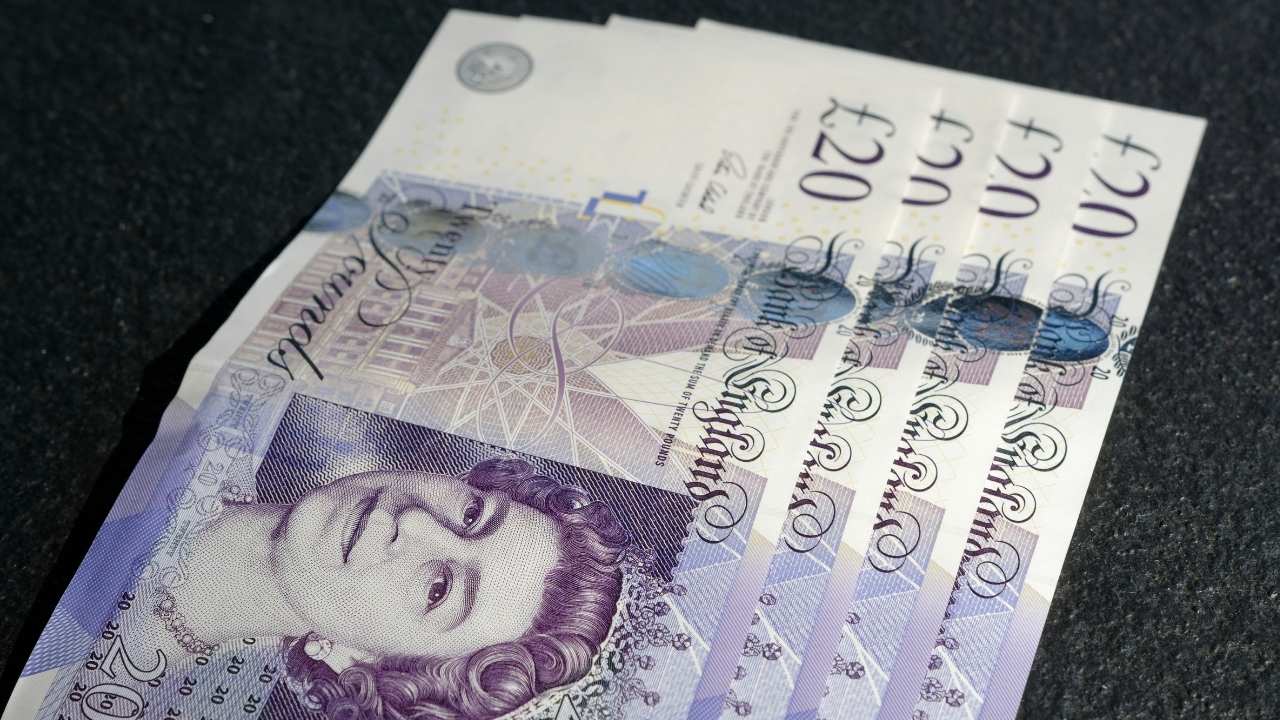 Four £20 bills on a black surface