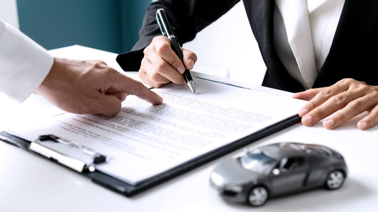 Man wearing a black blazer signing a contract on a table