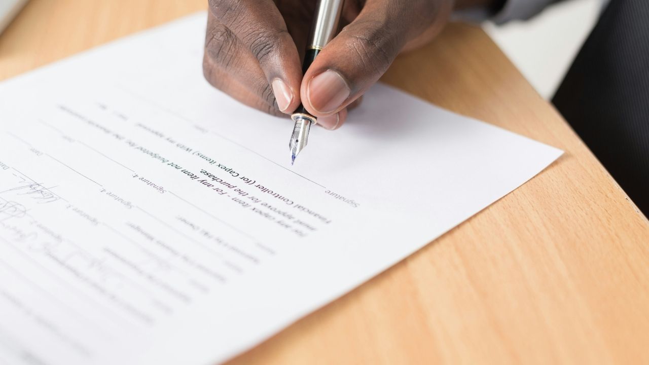 Man signing a contract on a wooden table