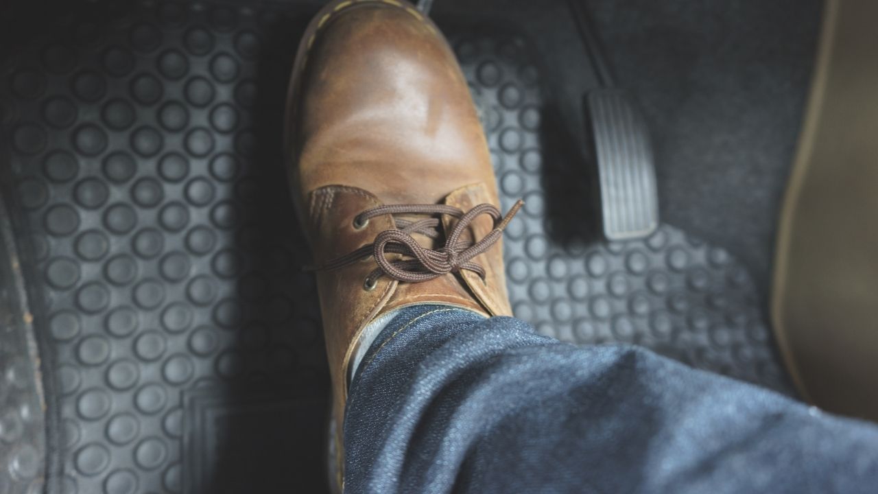 Man wearing brown boots stepping on a car pedal