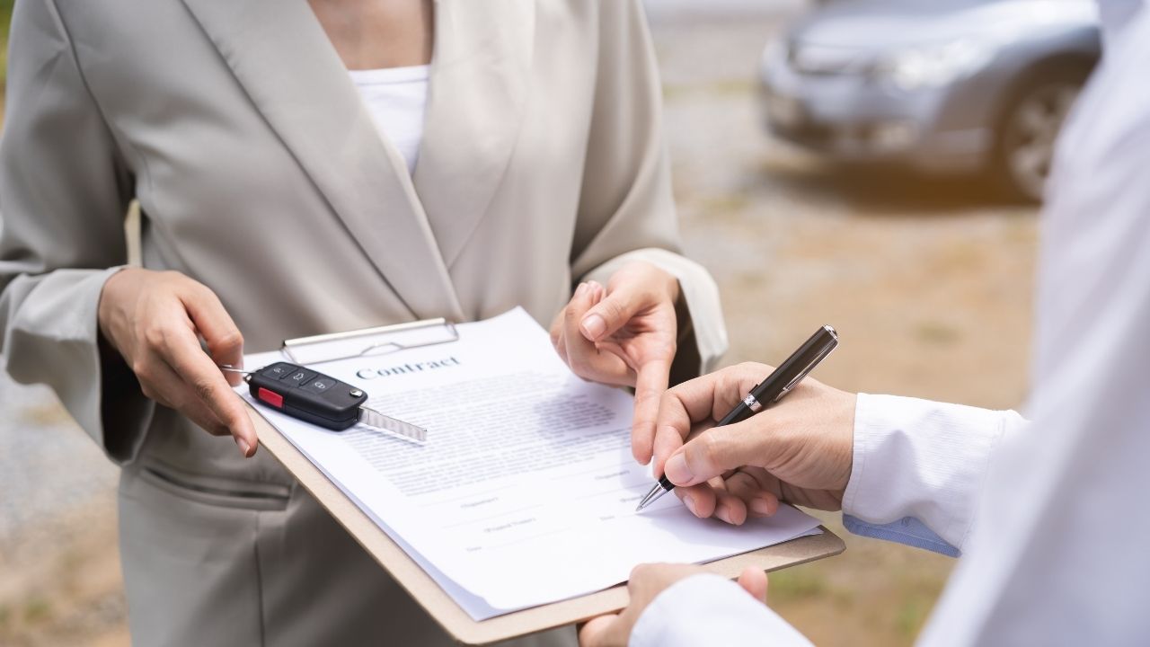 Man signing a contract that a woman is holding