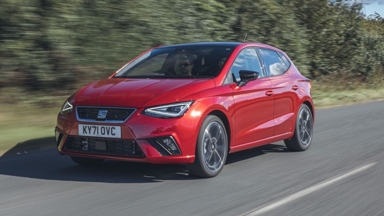 Red SEAT Ibiza driving in a motorway with trees on its left side