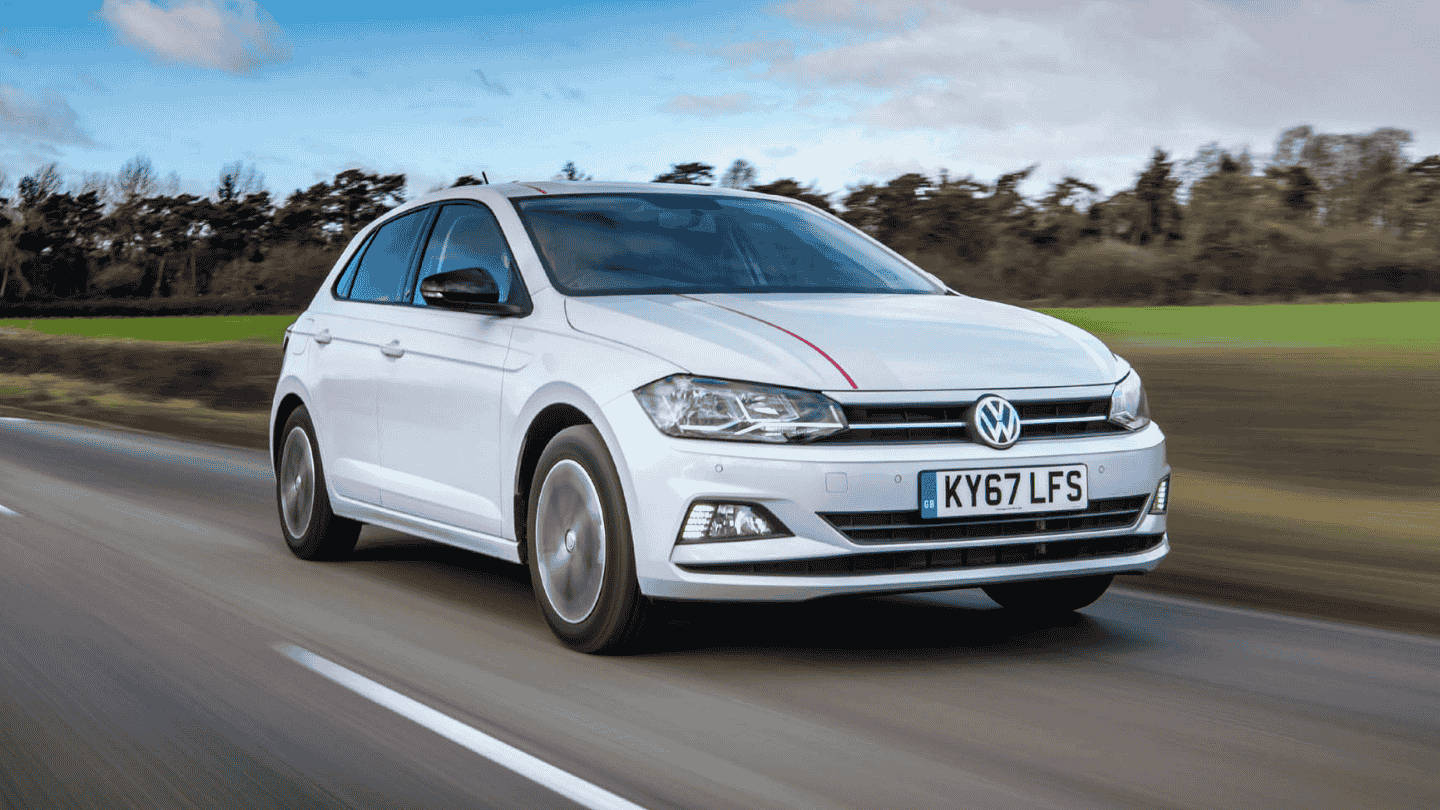 White Volkswagen Polo driving in a motorway with green grass and trees on its right side